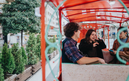 Teenage friends ride a decorative city tram and chat during a casual urban outingの写真素材