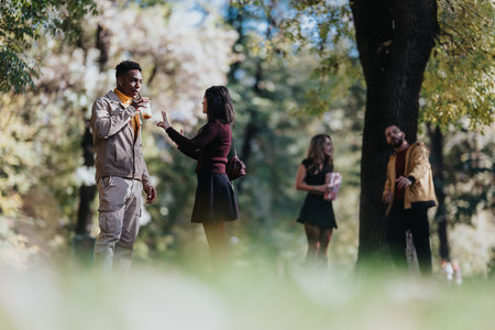 Diverse friends chat in a sunny park, enjoying a casual outdoor gatheringの写真素材