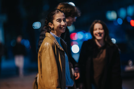 Friends enjoy a night out outdoors, smiling and chatting under street lights in a city setting