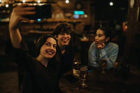 Three friends enjoy a night out, taking a selfie at a cozy bar.の写真素材