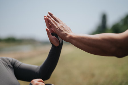 Two individuals giving a high five outdoors on a sunny dayの写真素材