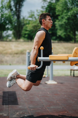 Fit man exercising on parallel bars in outdoor gym during sunny day