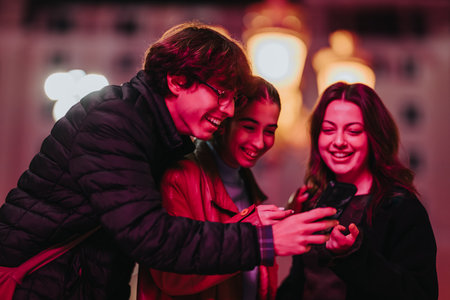 Friends enjoying a night out, looking at a phone, smiling and sharing moments together