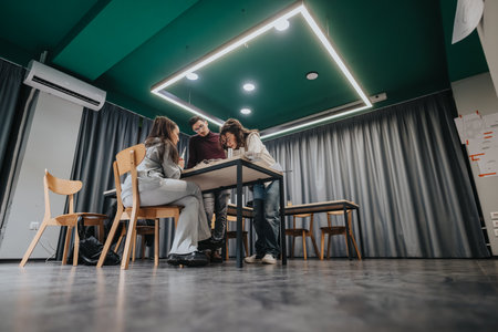 Students collaborate around a table in a modern study room, working on a group project.