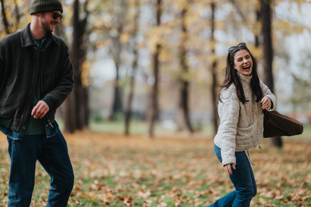 Joyful autumn moment: friends laughing and strolling in the park among colorful leavesの写真素材