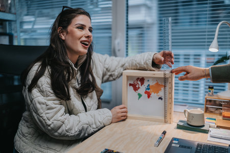 Young woman studying geography in a cozy office with a world map frame and rulerの写真素材