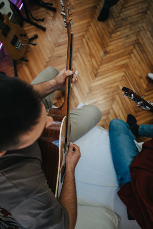 Guitar player practices acoustic guitar in a studio with other guitars around during rehearsalの写真素材
