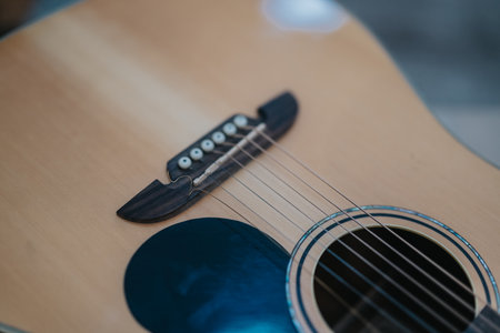 Close-up of an acoustic guitar bridge and strings with a visible sound hole for stock use