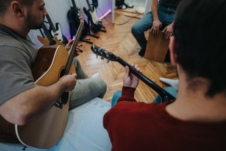 Friends sharing a casual jam session playing acoustic guitars in a cozy home roomの写真素材