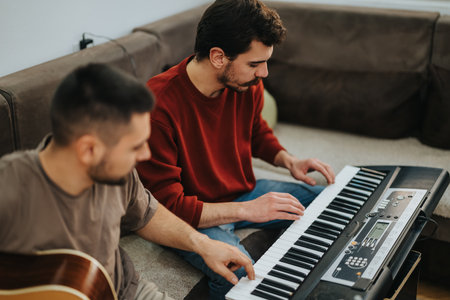 Two friends play keyboard and guitar in a cozy living room during a casual jam sessionの写真素材