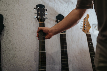 Close-up of a hand gripping a guitar neck with multiple guitars in a row in a studio settingの写真素材