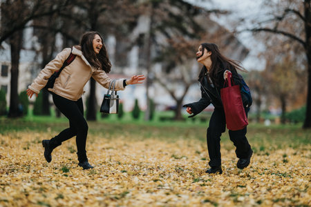 Two teenage girls laugh and run in a park as autumn leaves fall, showcasing friendship
