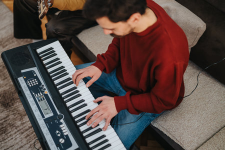 Man playing keyboard at home in a red sweater, enjoying a quiet music session