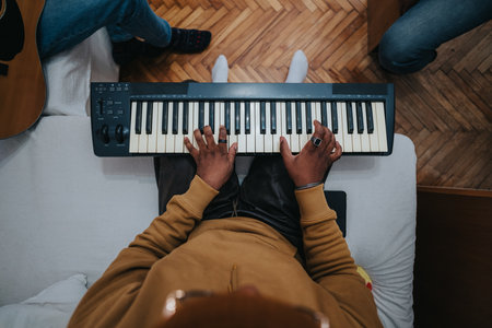 Person playing electronic keyboard from a top-down view on a couch indoorsの写真素材