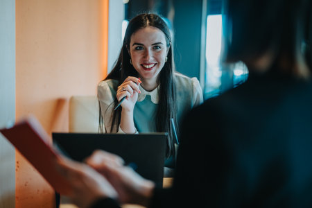Smiling woman and coworker discuss documents during a casual business meeting at a cafeの写真素材