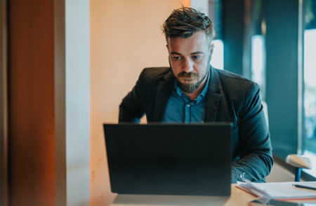 Businessman works on laptop in a modern office during a morning work session, focused and productive