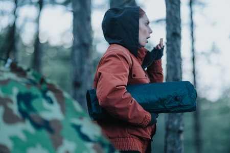 Woman in red jacket carrying camping mat in forest during outdoor hiking adventure