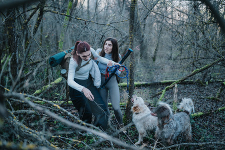 Two women hiking with dogs in a misty forest, enjoying an outdoor adventure.