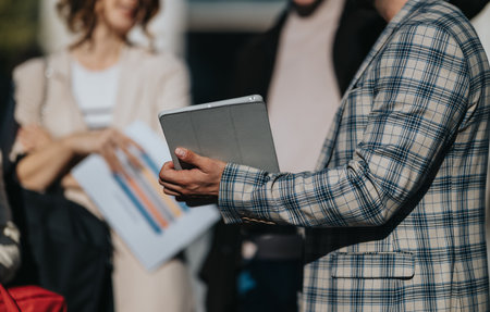 Business professional holds tablet during a meeting with colleagues in a city setting