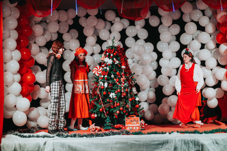 Christmas theater show with performers on stage around a decorated tree and giftsの写真素材