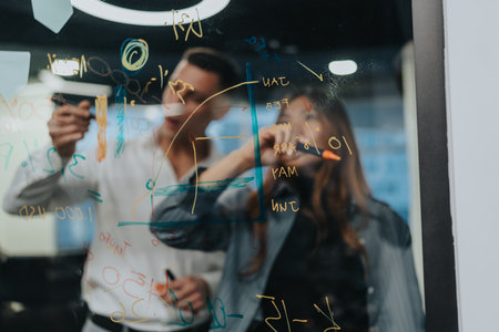 Business team brainstorming on glass board with formulas in a modern office
