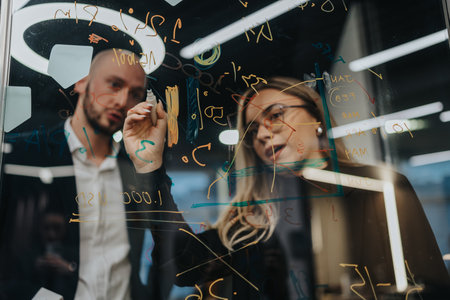 Business brainstorming on a glass board with markers, two professionals collaborating on ideas