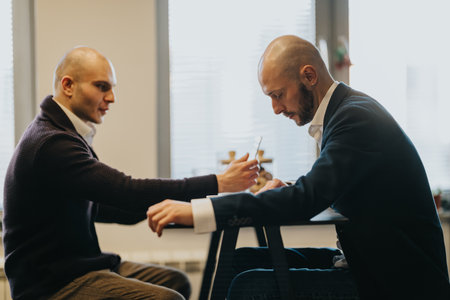 Two clean-cut men in a modern office share a focused moment at a desk during a business meeting