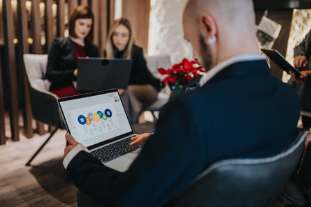 Business meeting in a modern office with a man presenting on a laptop to colleagues