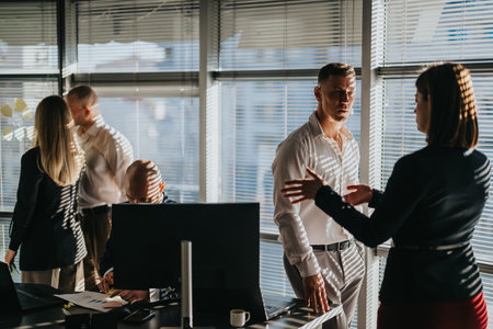 Professional colleagues discuss strategy in a modern office with blinds and morning lightの写真素材