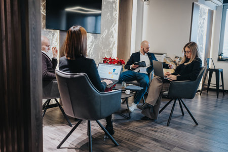 Professional group meeting in a modern office lounge with laptops, coffee, and relaxed atmosphere