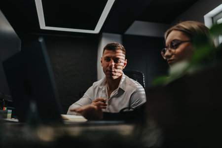 Business professional at desk discussing strategy with colleague in a modern office