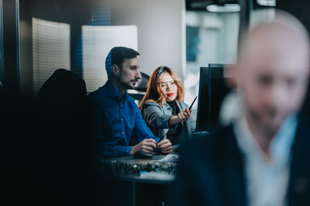 Business colleagues collaborate at a workstation, reviewing data on screens in a modern office