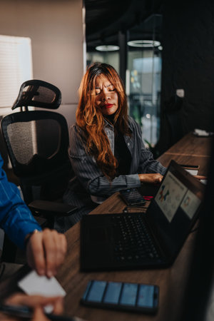 Woman at her desk deep in thought during office work with laptop and phone