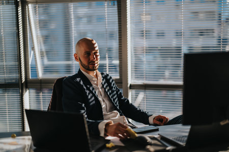 Businessman in a modern office working at his desk with laptop and documents