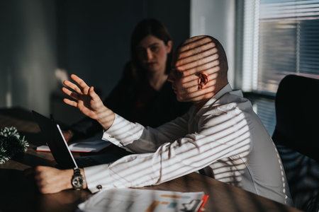 Business People Discuss Strategy in a Sunlit Office With Laptop and Documents
