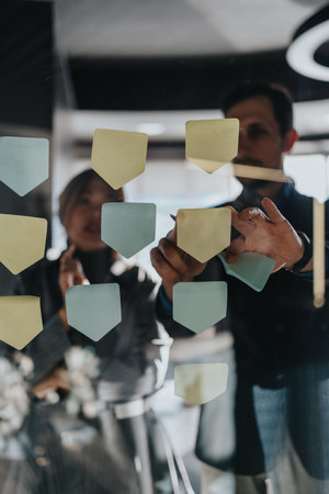 Team brainstorming session with sticky notes on glass wall during collaboration