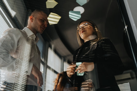 Professional coworkers discuss ideas in a glass-walled office with decorative notes