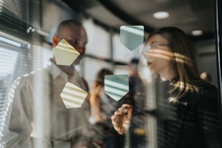 Business team discusses ideas through glass wall with colorful stickers in modern office