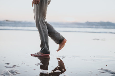 Barefoot walk on a sunlit beach with calm water and reflection at sunset