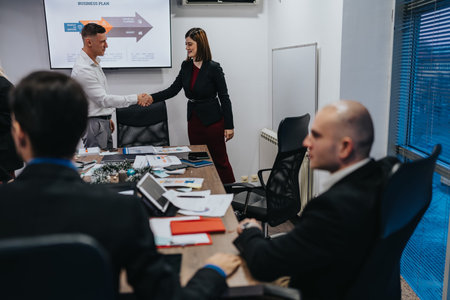 Business partners shake hands after a meeting in a conference room during a corporate planning...