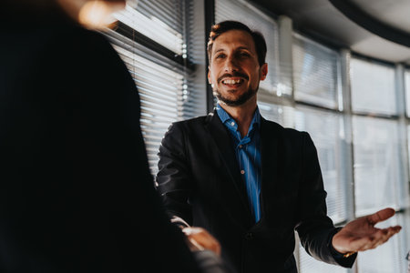 Smiling professional man in blazer greets colleague during a business meeting in a modern office