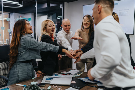 Diverse team celebrates together around a conference table with hands joined in unity