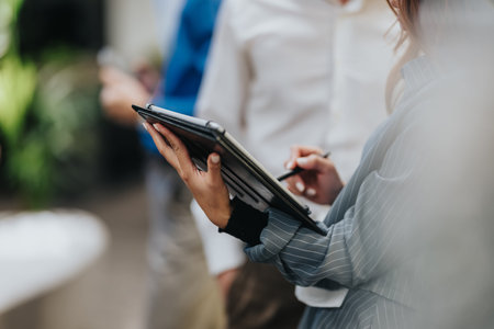 Business professional writes on a clipboard during an indoor meeting setup for planning