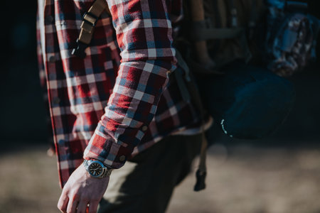 Man in red plaid shirt with backpack and watch walking outdoors in natureの写真素材