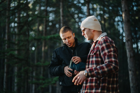 Two friends in a forest discuss gear and prepare a backpack outdoorsの写真素材