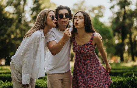Three friends share a playful outdoor moment in a sunny park settingの写真素材