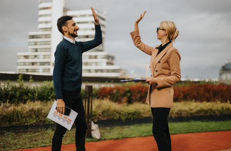 Business partners celebrate with a high-five outdoors in a modern urban setting