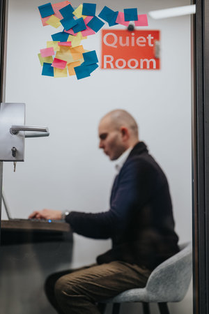 Business professional works at a desk in a quiet room with colorful sticky notes on the door