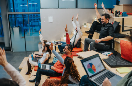 Team of professionals raises hands in a lively workshop during a modern office meeting today