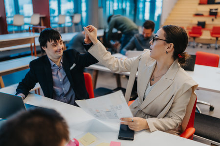 Business colleagues celebrate success with a high five at a bright, modern office during a teamwork...